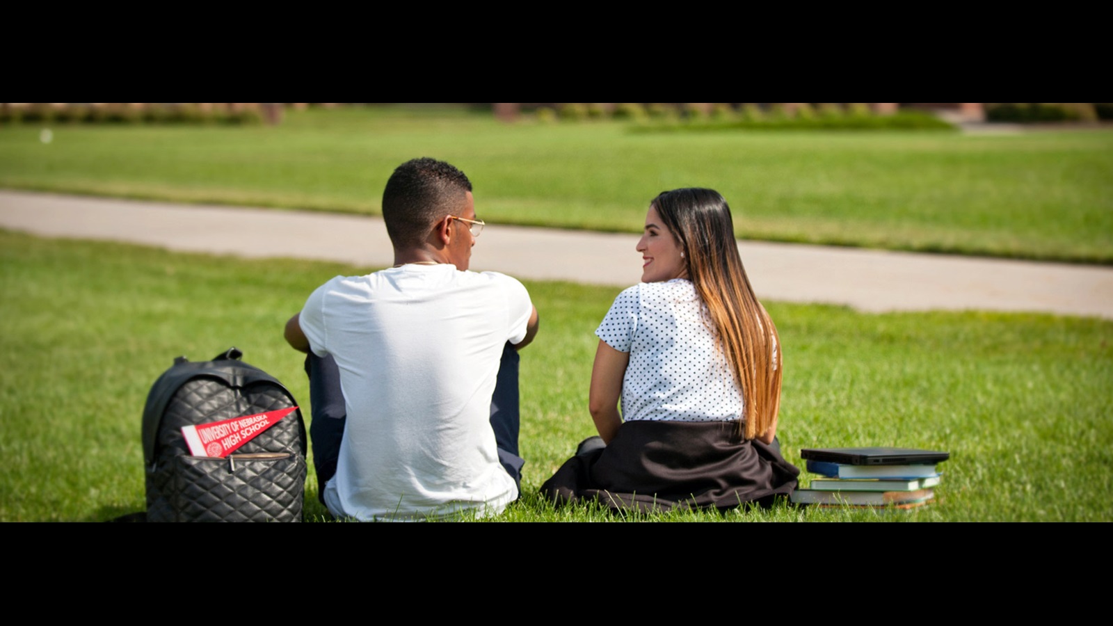 Two UNHS students sitting on lawn talking