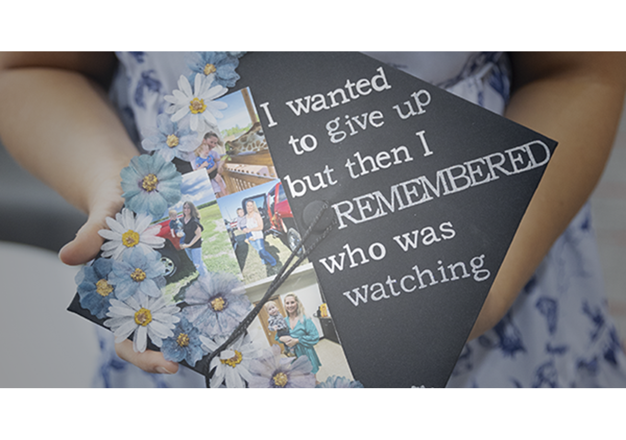 Graduate Expressions image, graduate holding decorated graduation cap, Hybrid Graduation Experience 2025